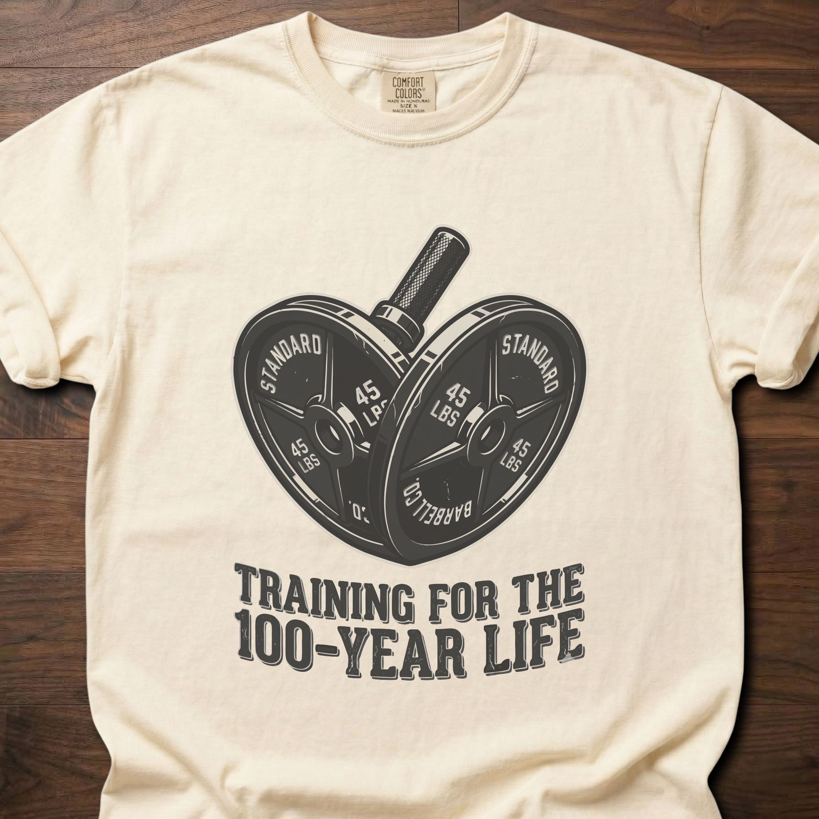 100-Year Life strength training t-shirt featuring heart-shaped weight plates and barbell design – Ivory