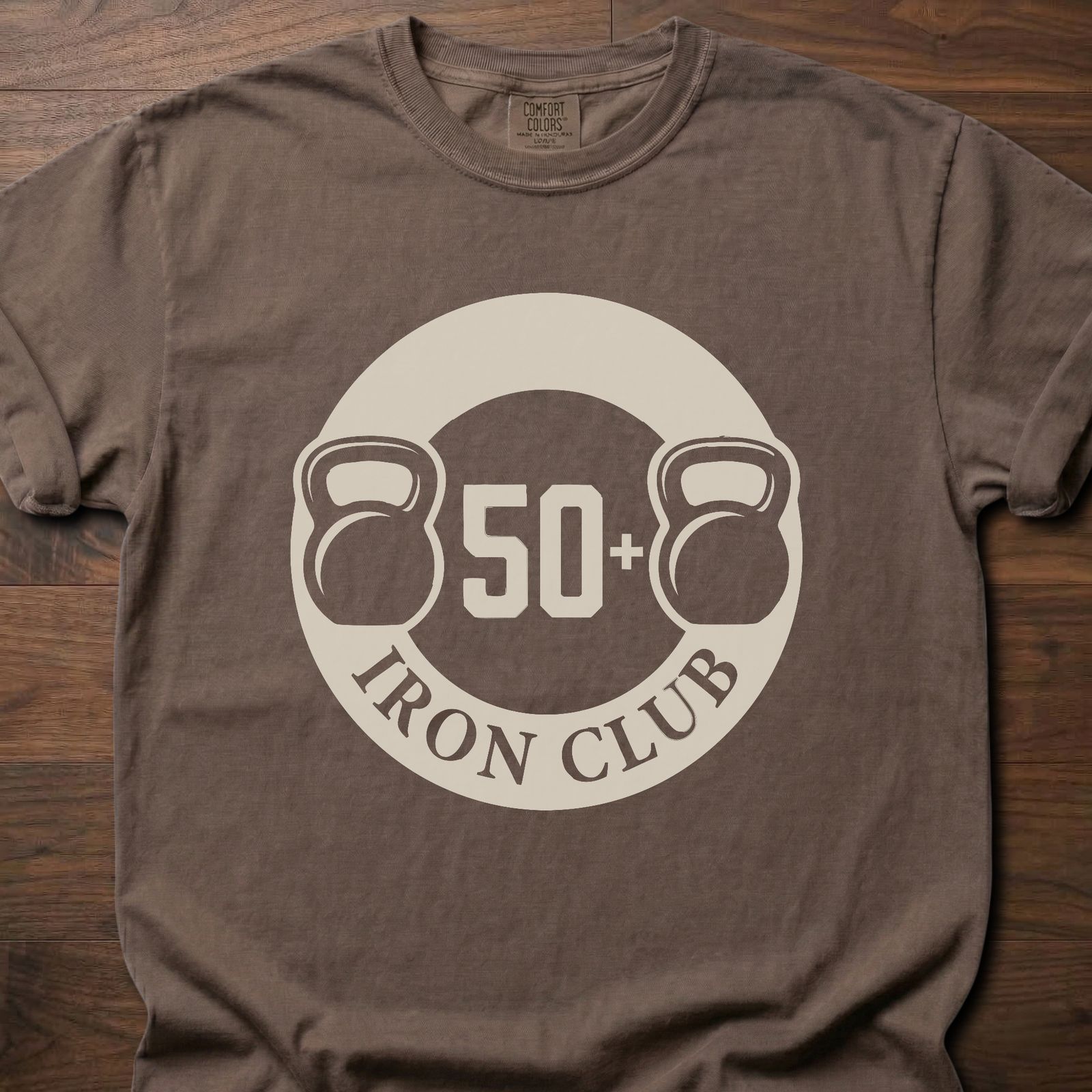 50+ Iron Club strength training t-shirt featuring kettlebells and circular badge design – Espresso