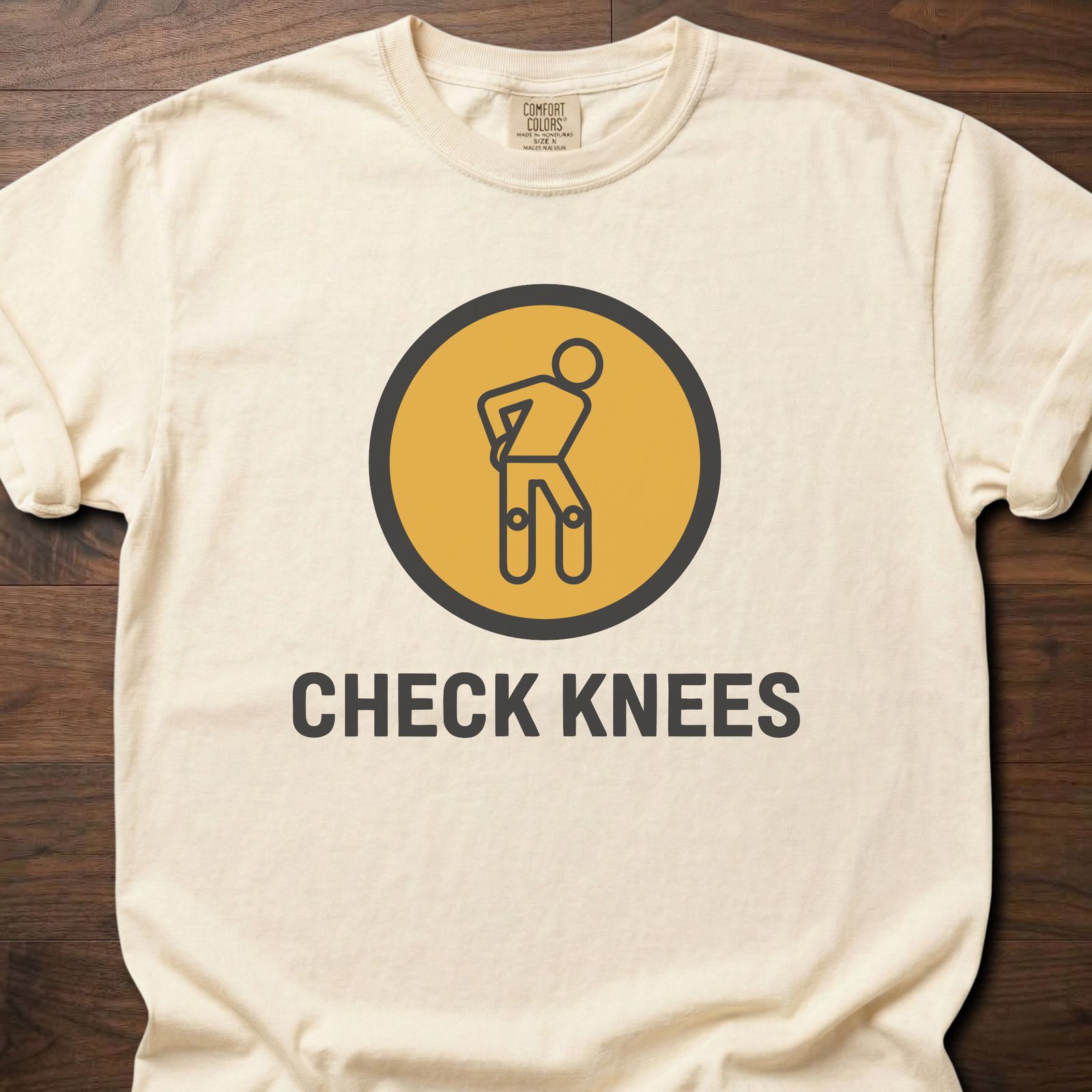 Check Knees strength training t-shirt with figure holding knee in circular badge design – Ivory