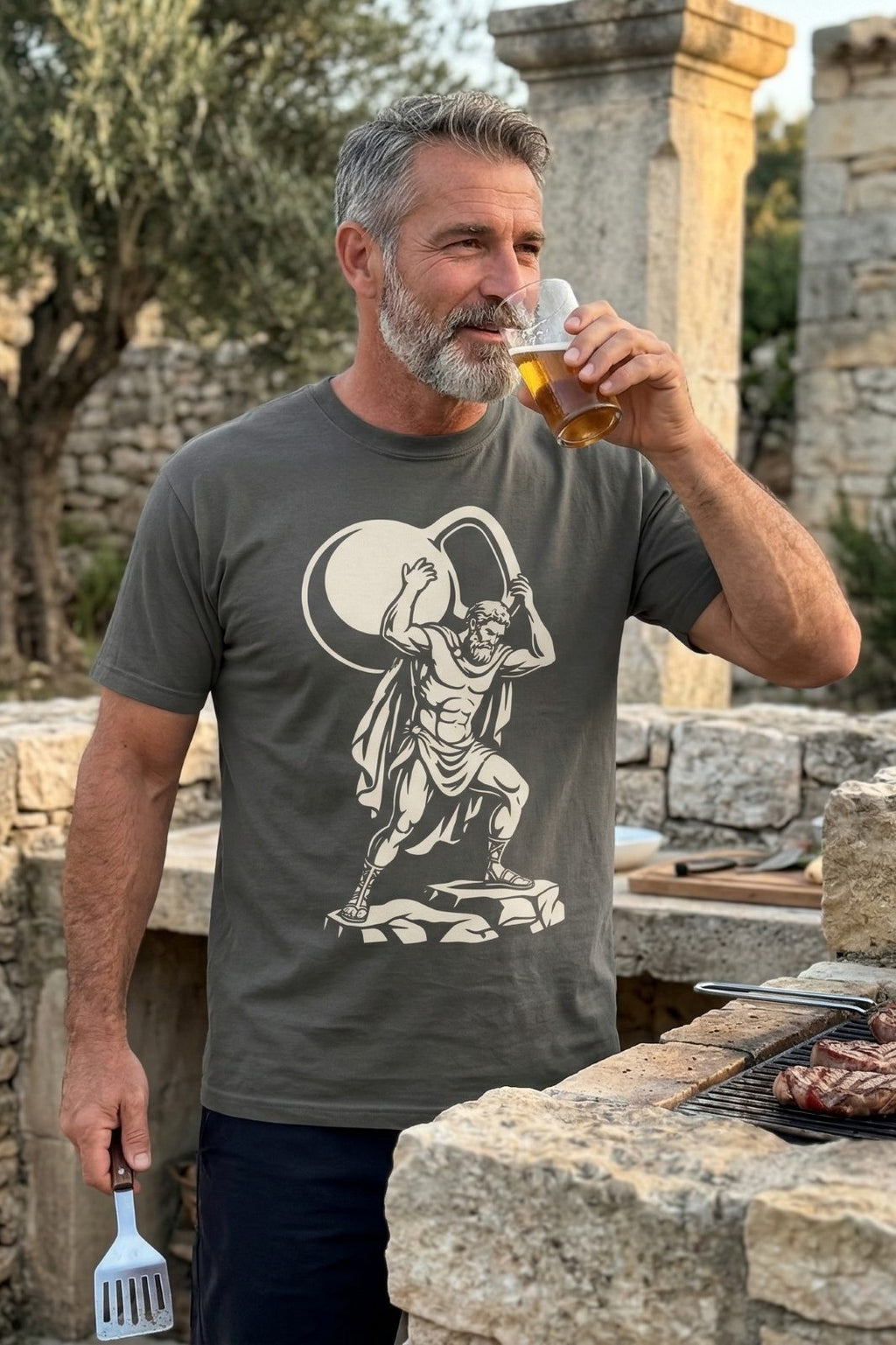 Man drinking beer and grilling outdoors wearing the Atlas Kettlebell t-shirt.