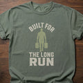 Built For The Long Run fitness lifestyle t-shirt with a figure carrying loaded farmer's walk handles – Moss