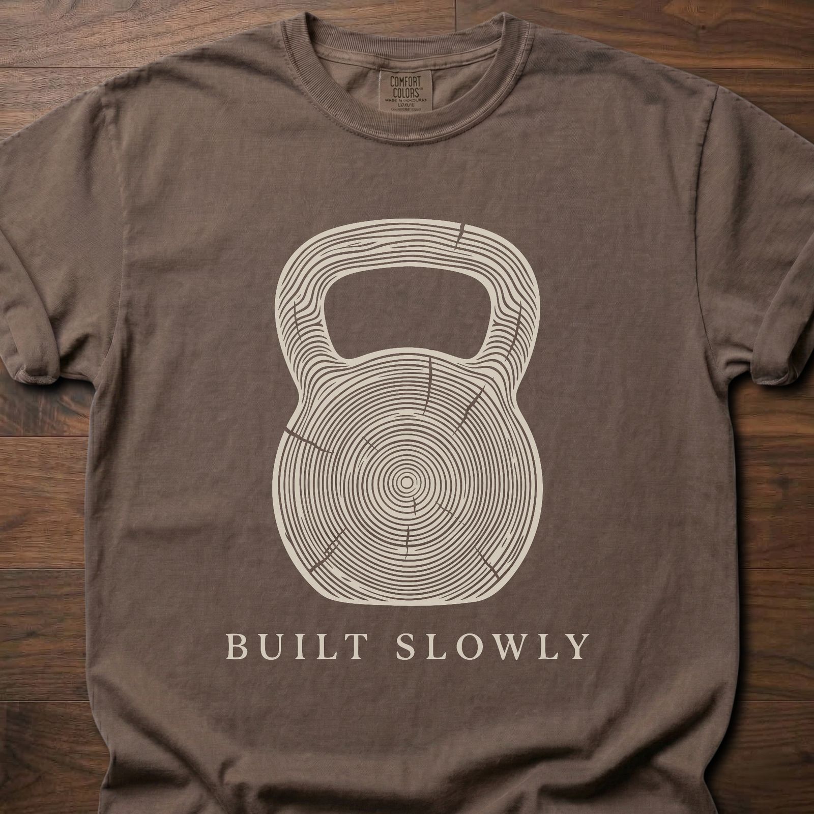Built Slowly fitness lifestyle t shirt featuring kettlebell with tree ring growth pattern design – Espresso