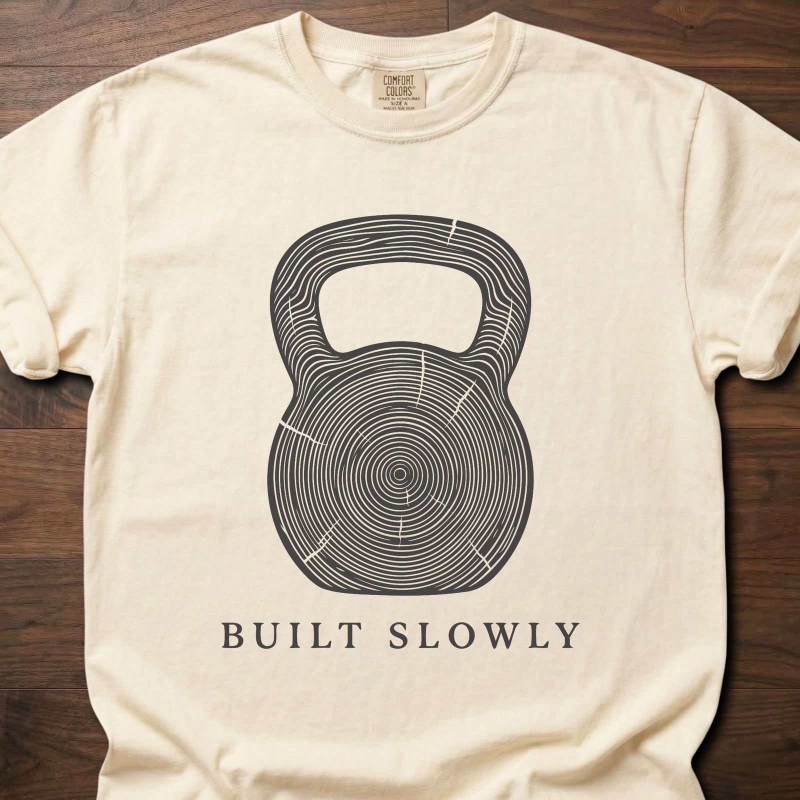 Built Slowly fitness lifestyle t shirt featuring kettlebell with tree ring growth pattern design – Ivory