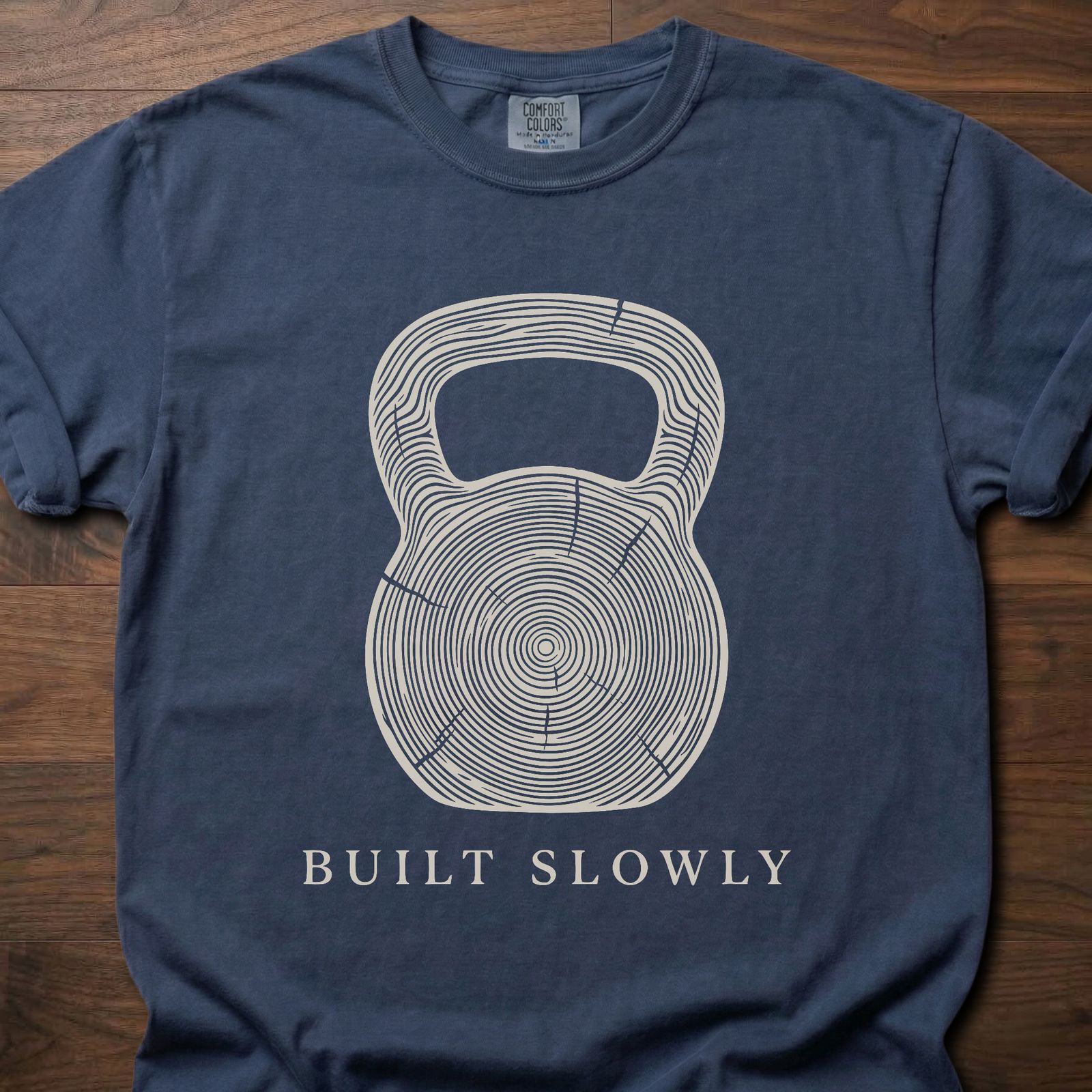 Built Slowly fitness lifestyle t shirt featuring kettlebell with tree ring growth pattern design – Navy
