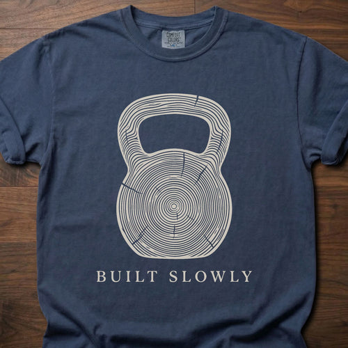 Built Slowly fitness lifestyle t shirt featuring kettlebell with tree ring growth pattern design – Navy