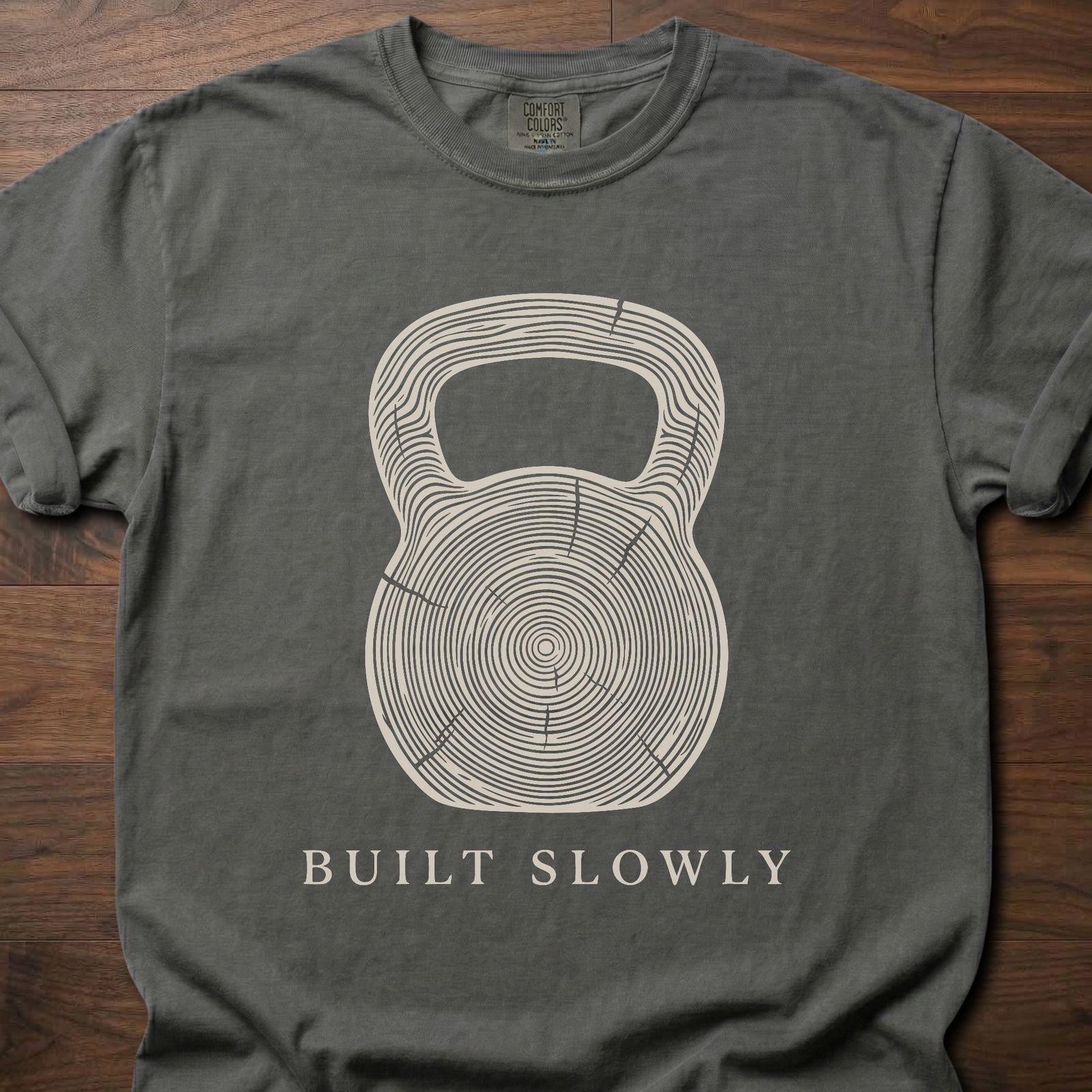 Built Slowly fitness lifestyle t shirt featuring kettlebell with tree ring growth pattern design – Pepper