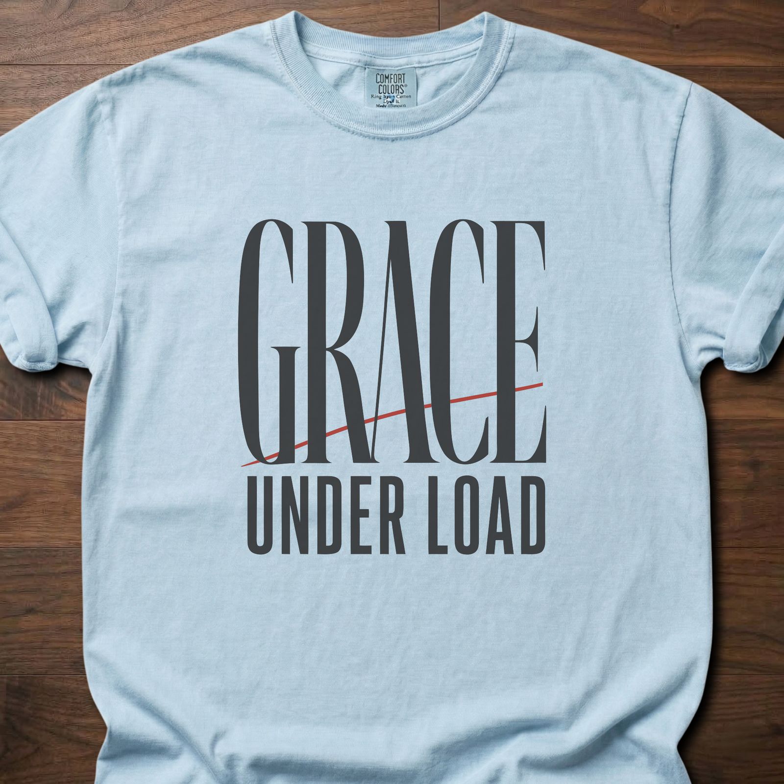 Grace Under Load strength training t-shirt with bold typography and red accent line design – Chambray