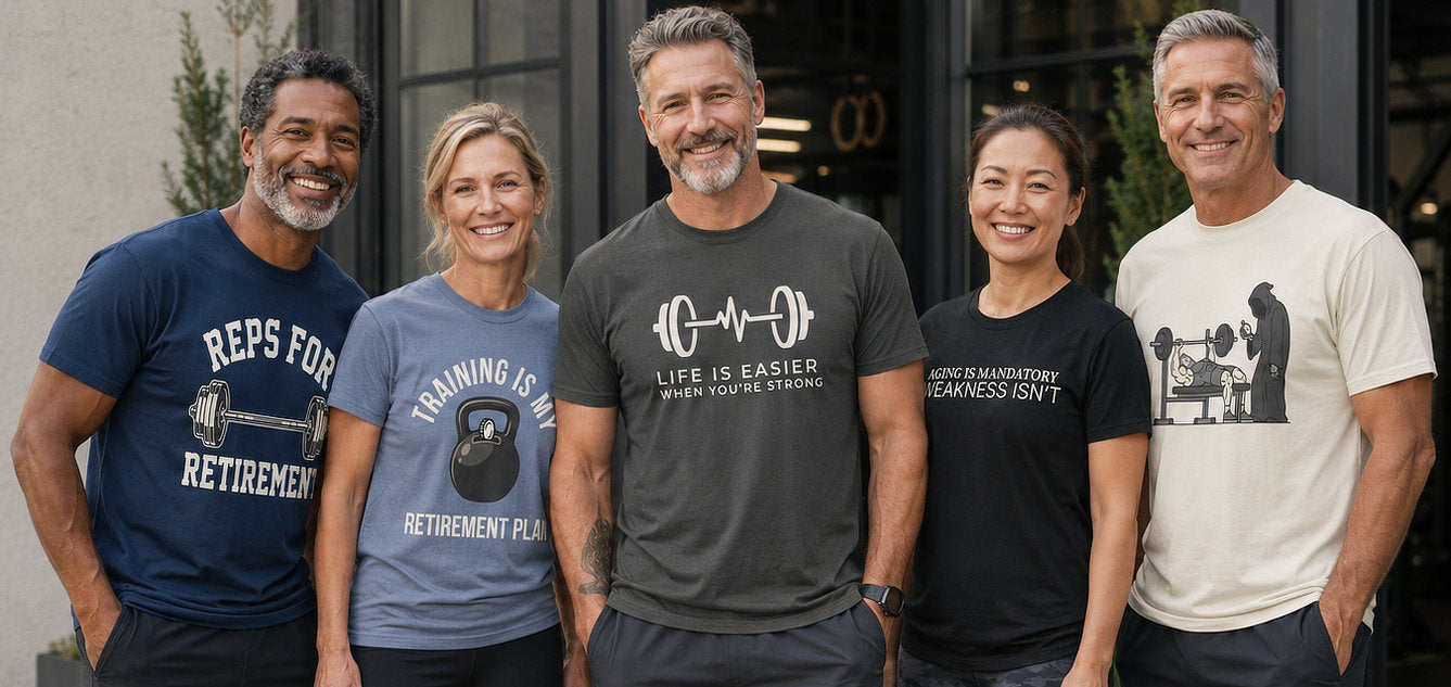Five people standing together outdoors in front of a building entrance, each wearing a graphic T-shirt. The shirts feature fitness and retirement-themed designs in navy, blue, gray, black, and off-white.