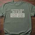 Staying Strong strength training t-shirt with bold vintage-style typographic graphic – Moss