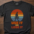 Use It Or Lose It strength training t-shirt with kettlebell walk and retro sunset graphic – Black